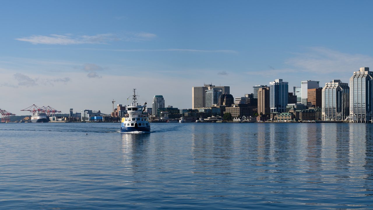 Wide panoramic view of the Halifax skyline and harbour under a bright blue sky