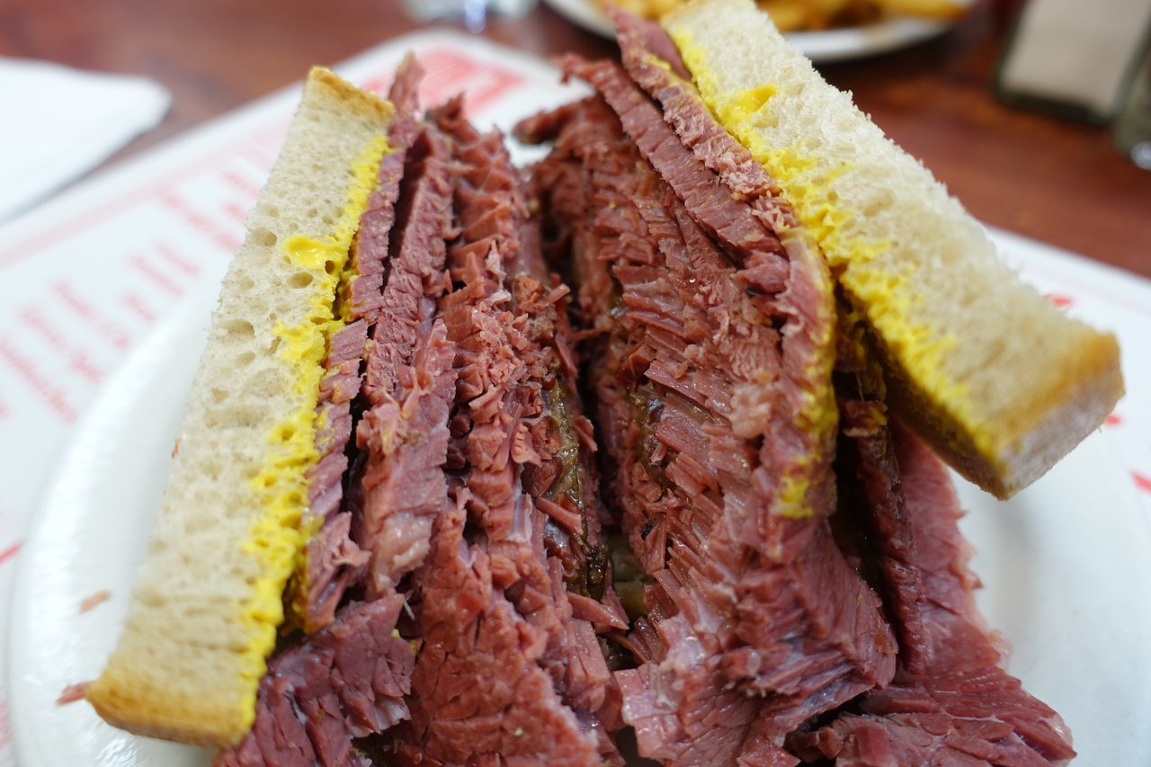 A classic Montreal smoked meat sandwich piled high on rye with a pickle and coleslaw