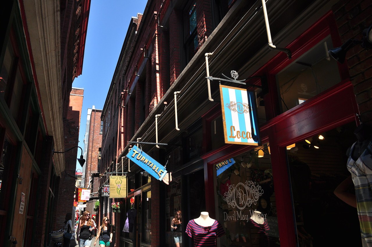 Shoppers walking through the narrow brick laneway of Fan Tan Alley in Victoria's Chinatown