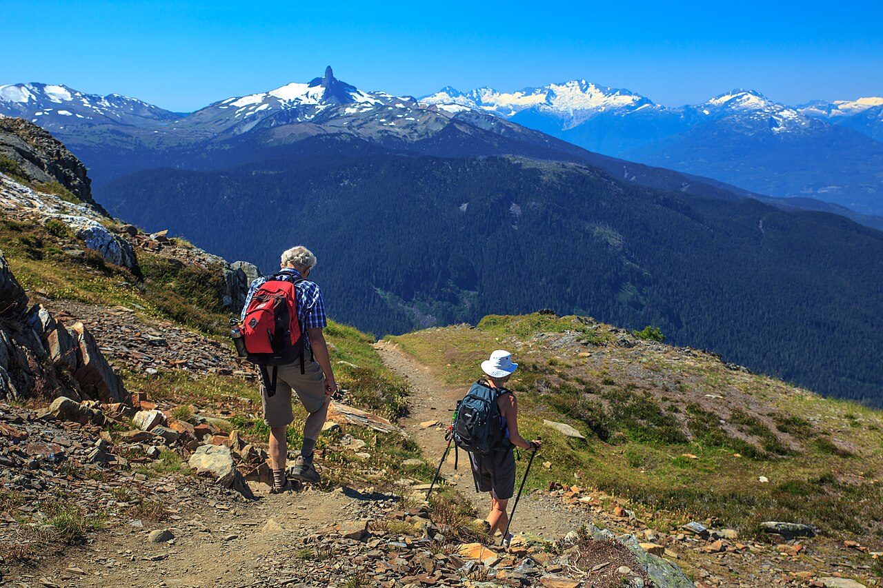 Hikers on the High Note Trail atop Whistler Mountain with the Black Tusk peak on the horizon