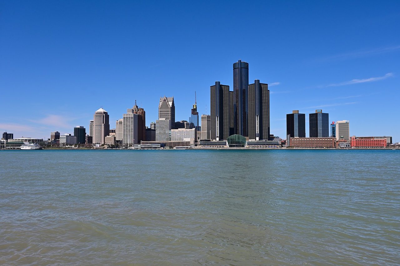 Detroit skyline glowing across the Detroit River at dusk, seen from Windsor's riverfront trail