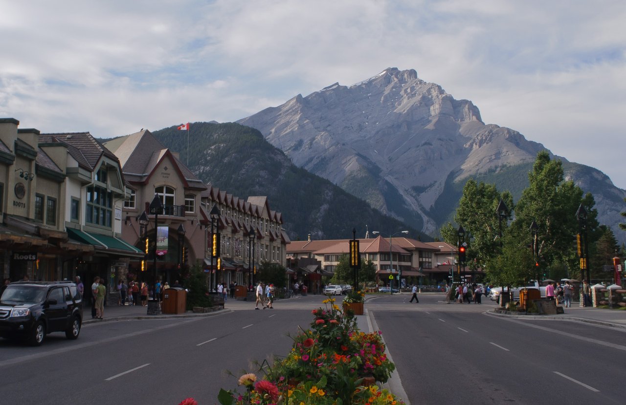 Banff Avenue lined with shops and restaurants, framed by Cascade Mountain on a sunny summer day