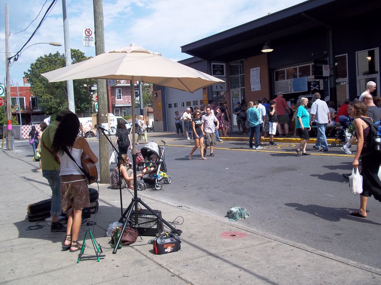 Buskers and weekend crowds outside the entrance of Marché Jean-Talon