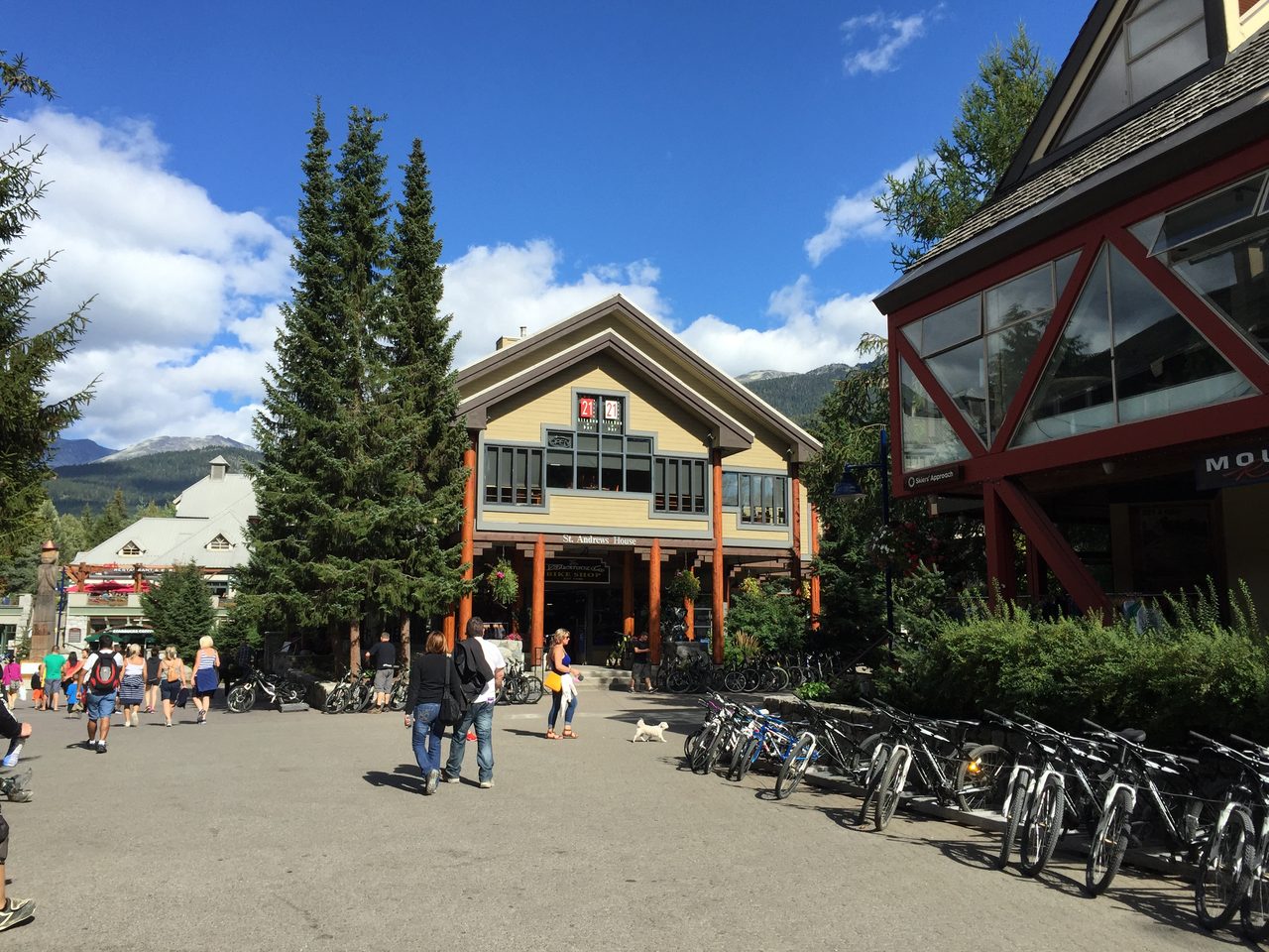 Whistler Village in summer with mountain peaks rising behind the pedestrian village