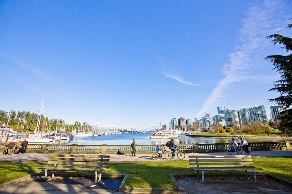 Cyclists and benches on the Stanley Park Seawall with the city skyline