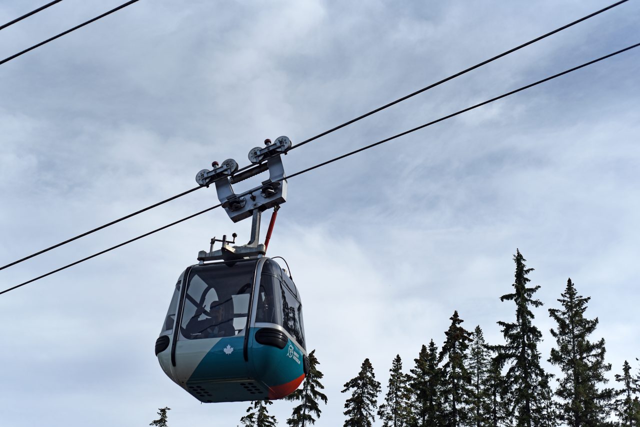 Teal Banff Gondola cabin gliding along the cable above spruce forest on Sulphur Mountain