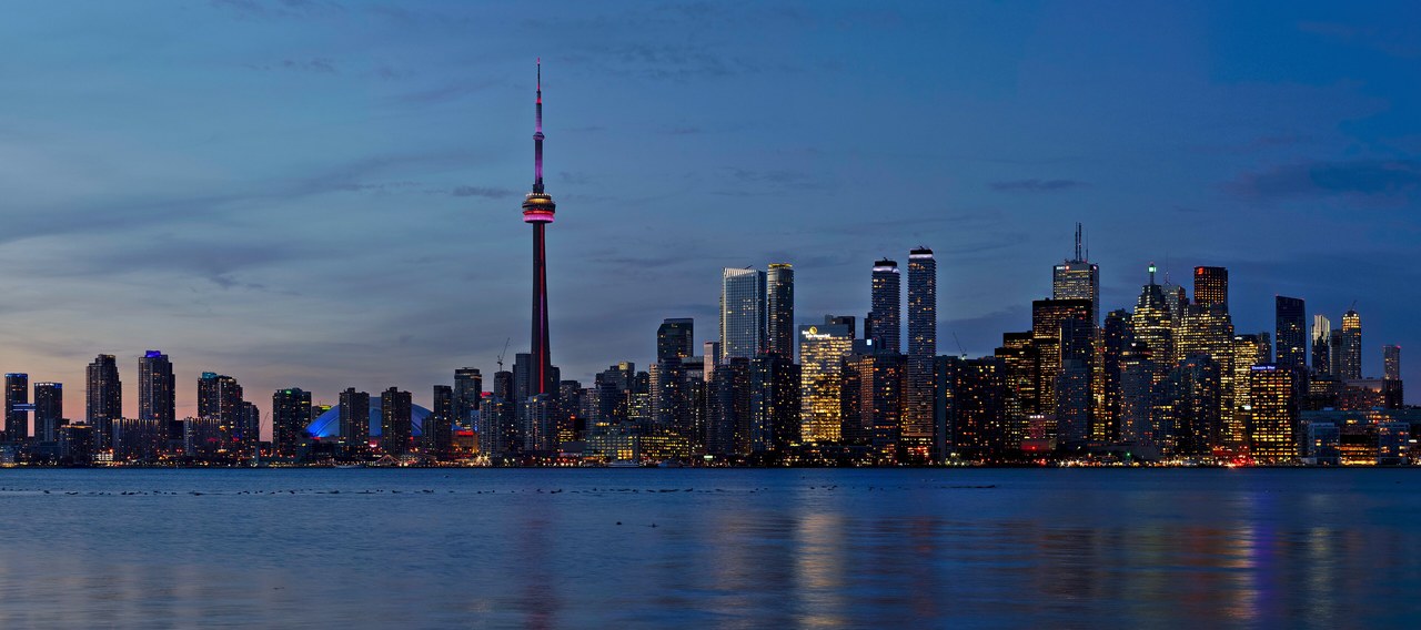 Toronto skyline glowing at sunset with the CN Tower, seen from across the harbour