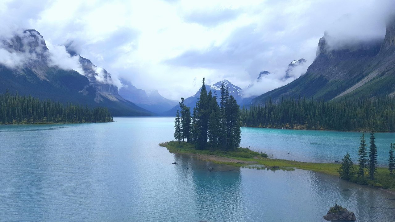 The tiny pine-covered Spirit Island on Maligne Lake in Jasper National Park, framed by misty mountain peaks