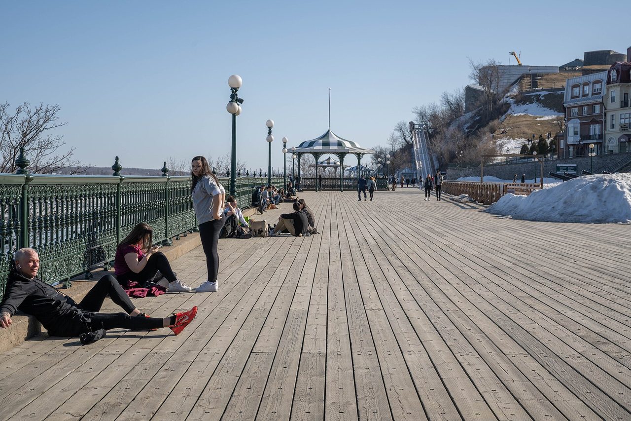 Visitors strolling along the wooden boardwalk of Dufferin Terrace beside the Château Frontenac