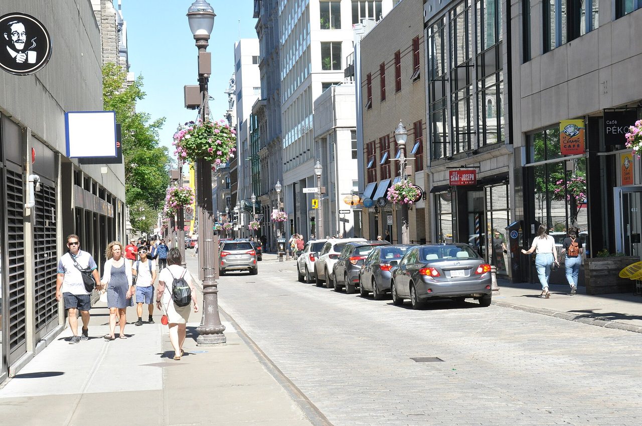 Sunny Rue Saint-Joseph in Saint-Roch with café storefronts, flower baskets, and pedestrians