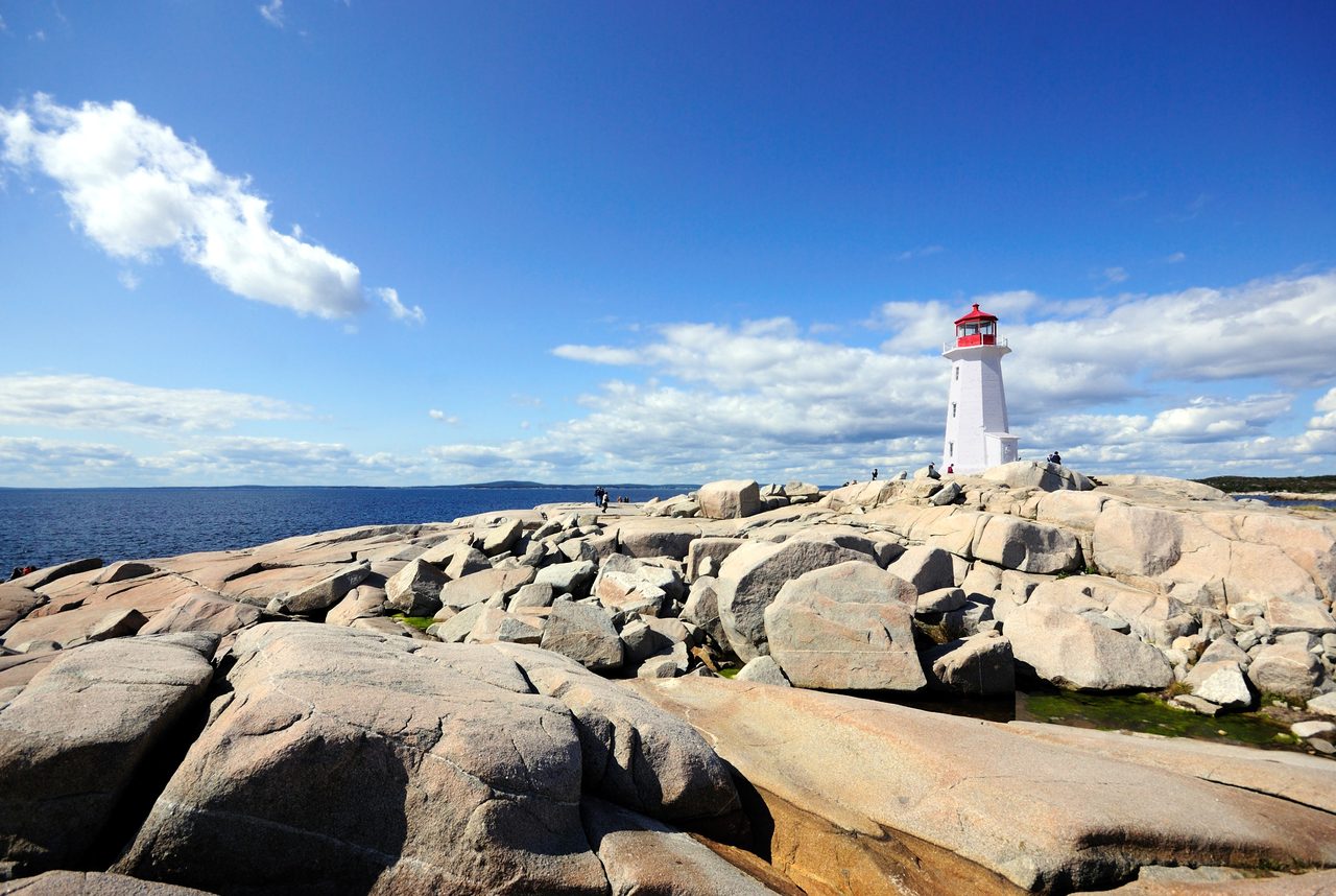 The iconic white-and-red Peggy's Cove lighthouse standing on wave-worn granite rocks above the Atlantic