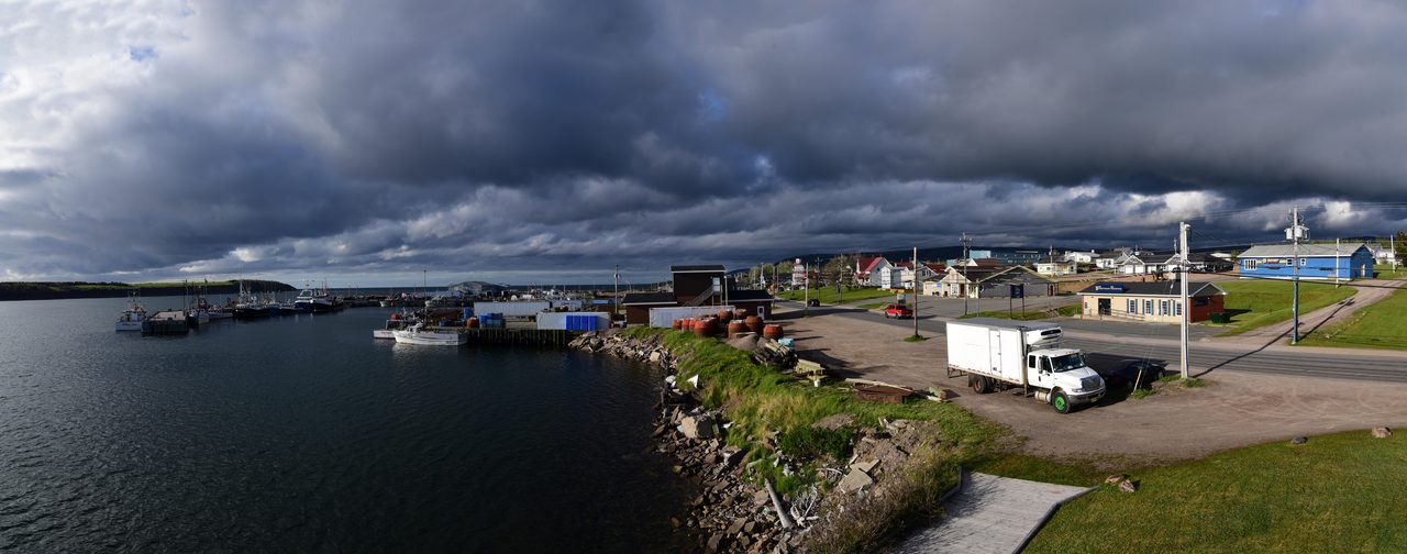 Fishing boats moored at the Chéticamp marina with hills rising behind the harbour