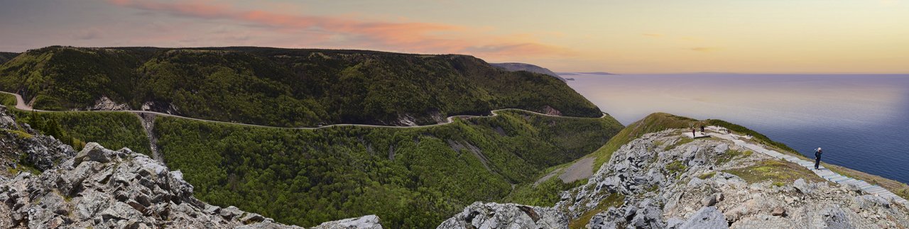 The Cabot Trail winding around forested headlands above the Gulf of St. Lawrence at sunset