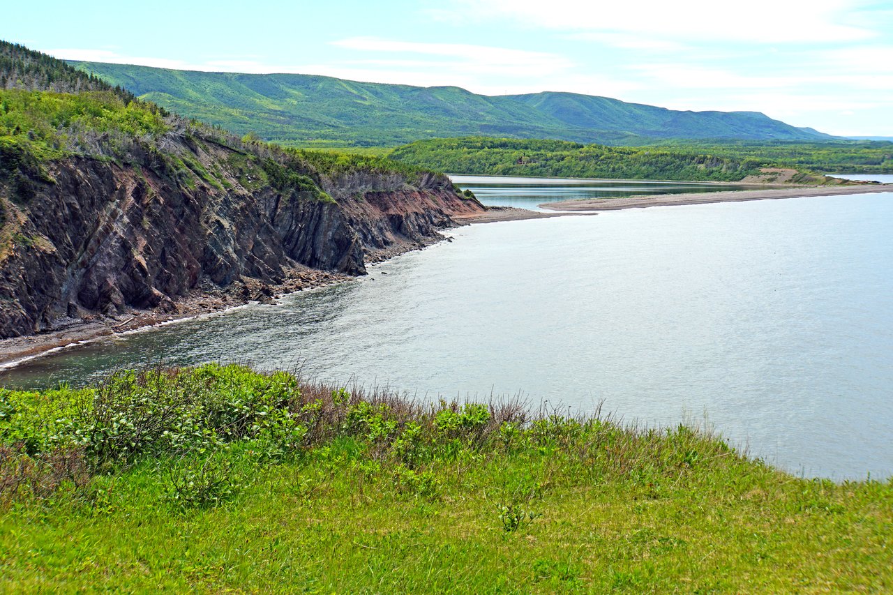 Rugged red cliffs and green hills along the Cabot Trail near Chéticamp, Cape Breton