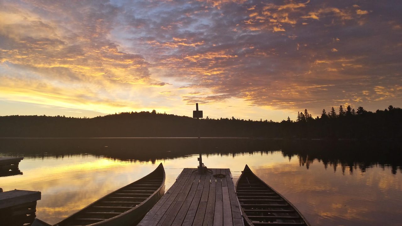 Canoe on calm water at Canoe Lake in Algonquin Provincial Park surrounded by pine forest