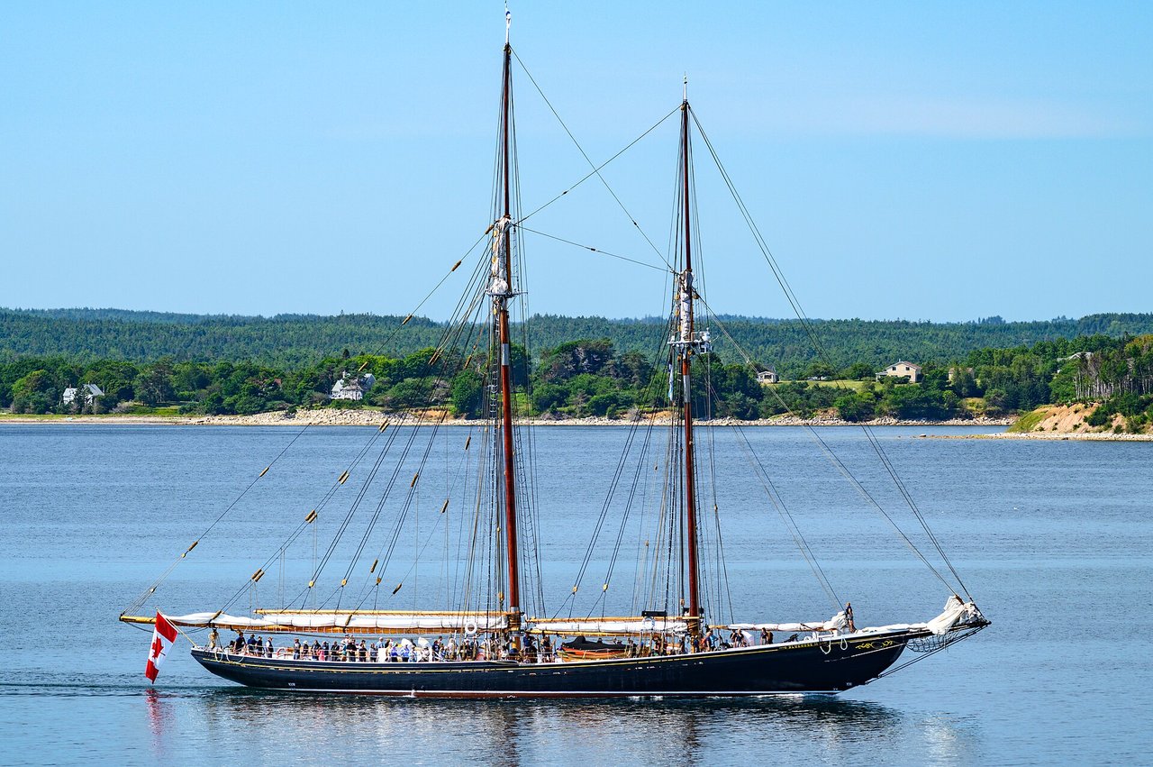 The Bluenose II sailing schooner arriving at Lunenburg harbour with full sails under a blue sky
