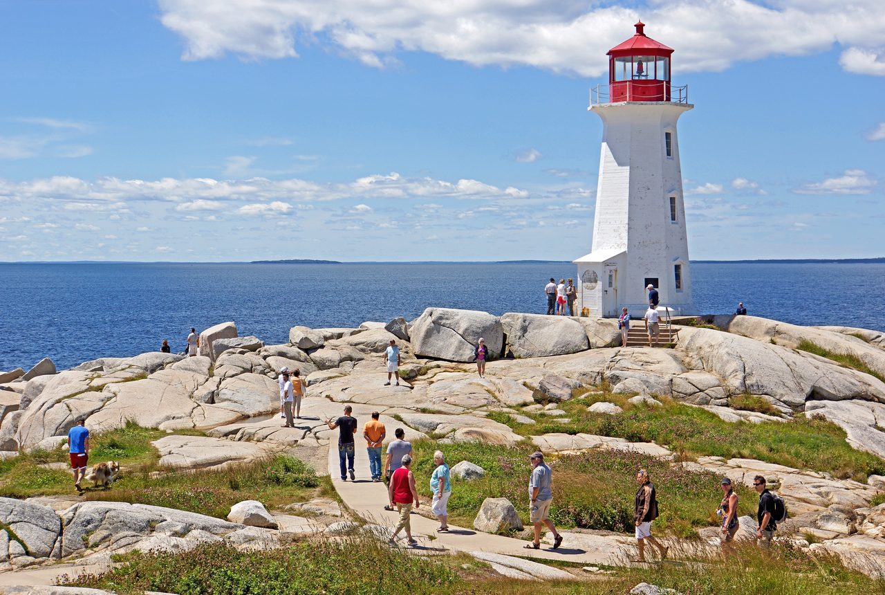 The white-and-red Peggy's Cove lighthouse standing on wave-worn granite rocks beside the Atlantic Ocean
