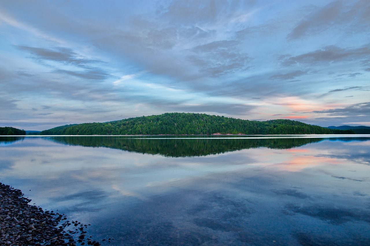 Still blue water and forested shoreline at Lake Manitou in Algonquin Provincial Park