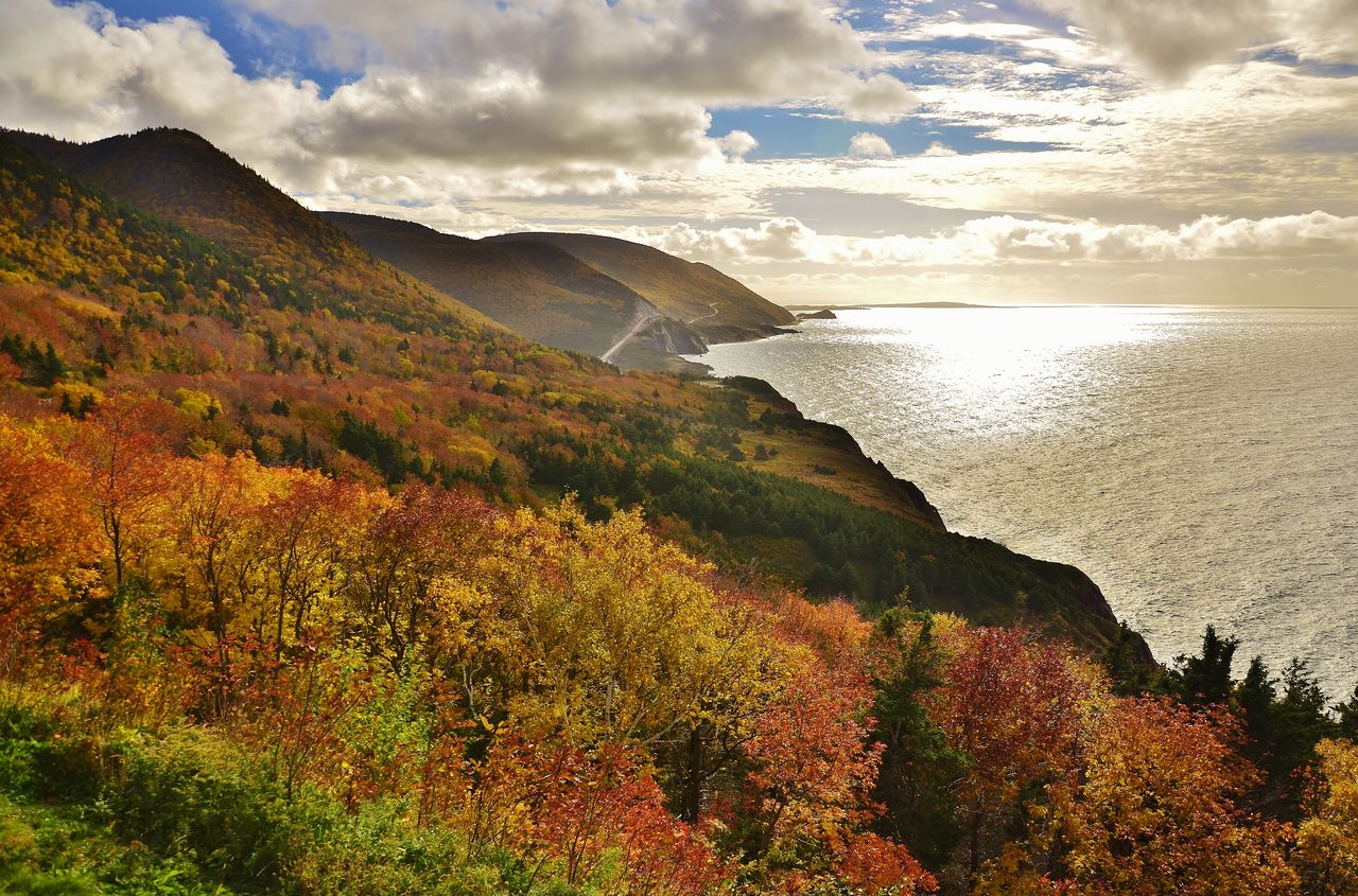 The Cabot Trail winding through brilliant red and orange autumn foliage on Cape Breton Island