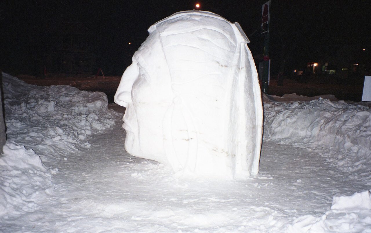 A smiling Bonhomme Carnaval decoration on a snowy street in Old Quebec during the Quebec Winter Carnival