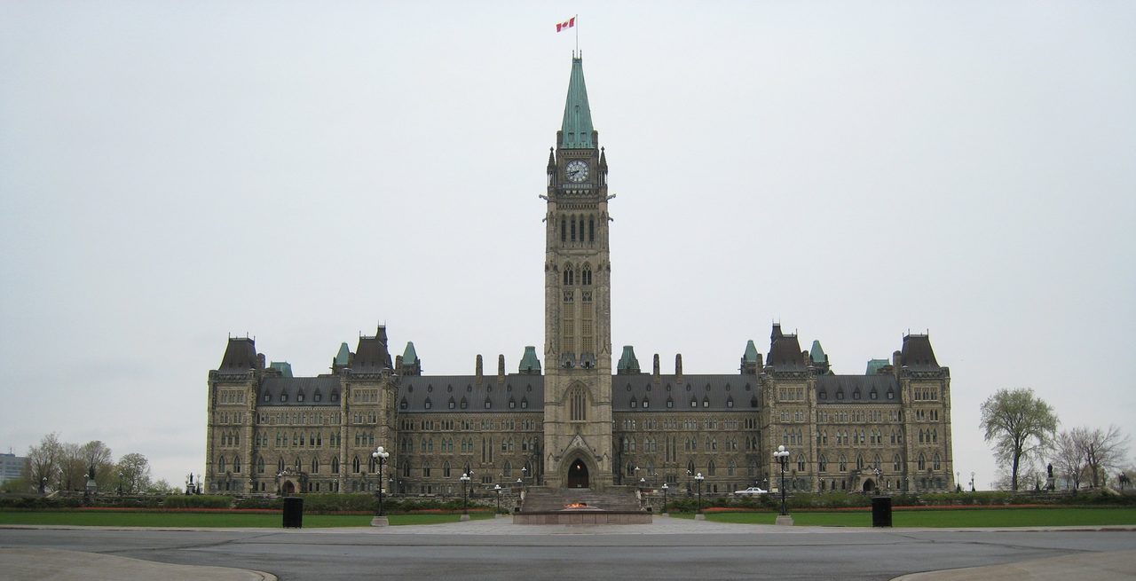 Parliament Hill's Peace Tower rising above the Centre Block in Ottawa, with spring tulips blooming in the foreground
