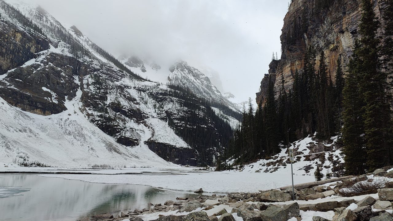 Lake Louise in spring with the Victoria Glacier and snowy peaks rising above blue-green water