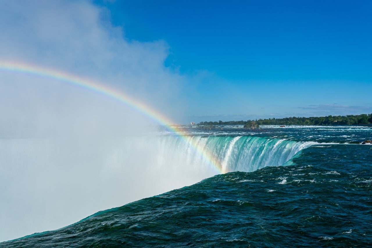 A bright rainbow arching over the mist of Horseshoe Falls at Niagara Falls