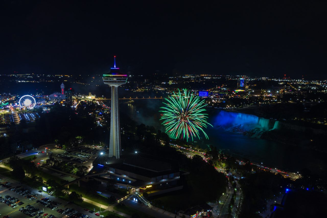 Fireworks bursting in bright colors over Niagara Falls at night