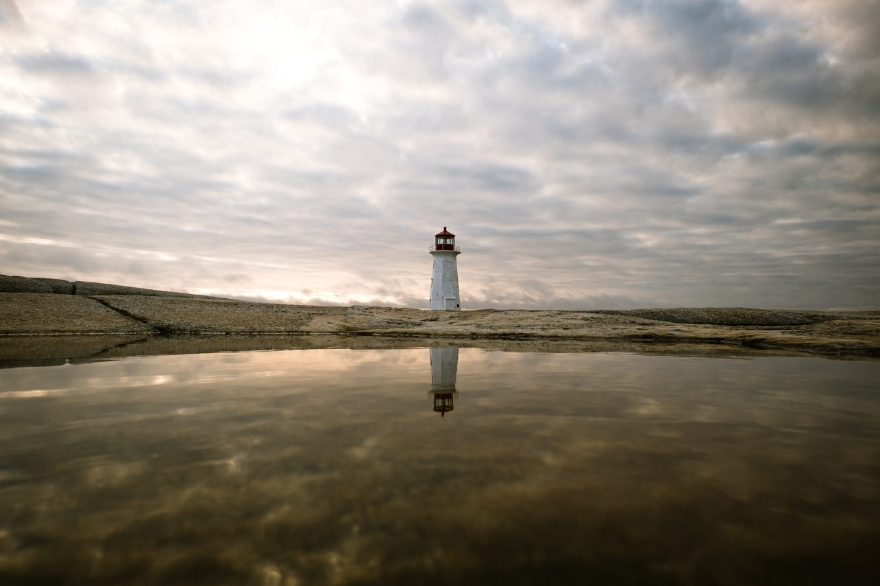 The red-and-white Peggy's Cove lighthouse standing on wave-washed granite rocks in Nova Scotia