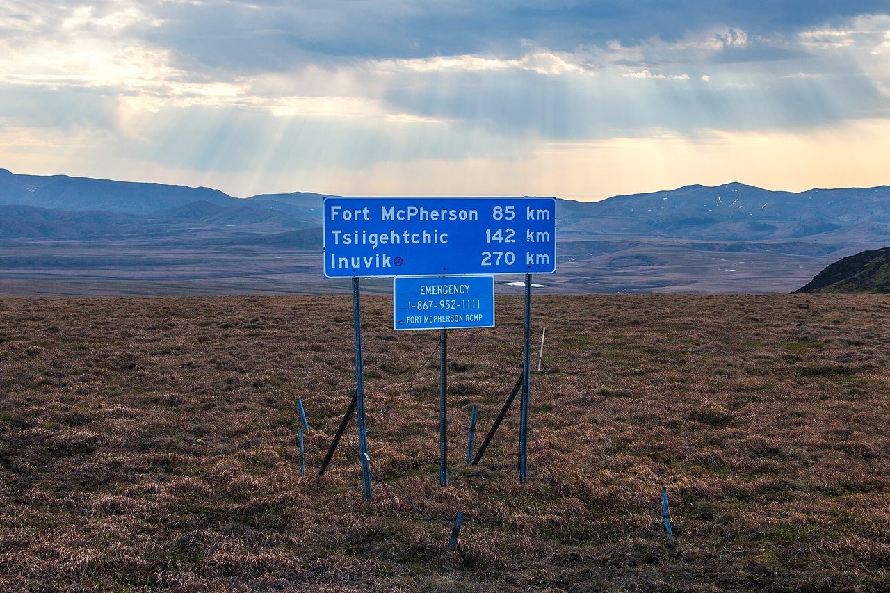 Gravel stretch of the Dempster Highway running through open tundra toward Tombstone Territorial Park, Yukon