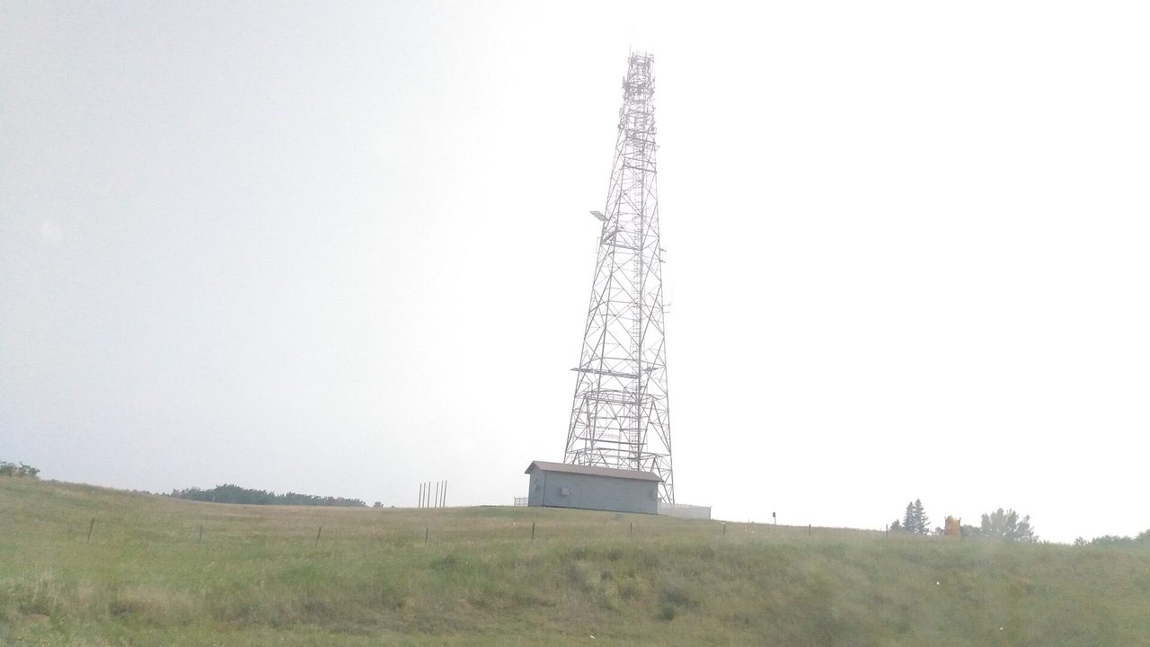 A SaskTel communications tower against a blue prairie sky