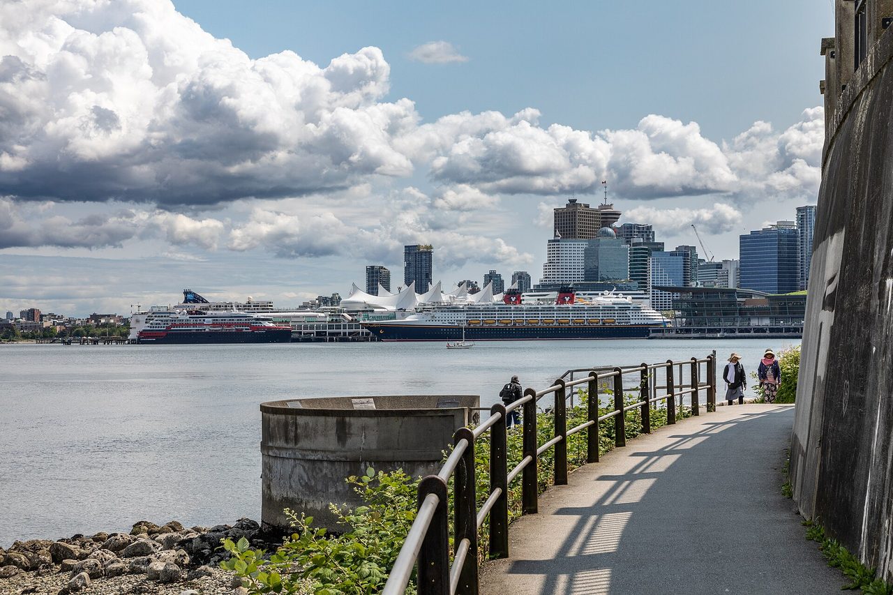 Cyclists on the Stanley Park Seawall path with Vancouver's harbour and skyline beyond