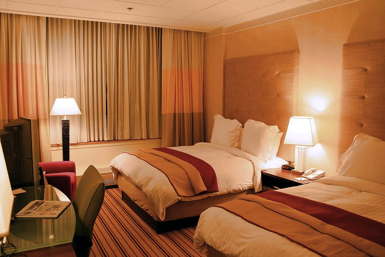 Warmly lit hotel room with two made beds and bedside lamps