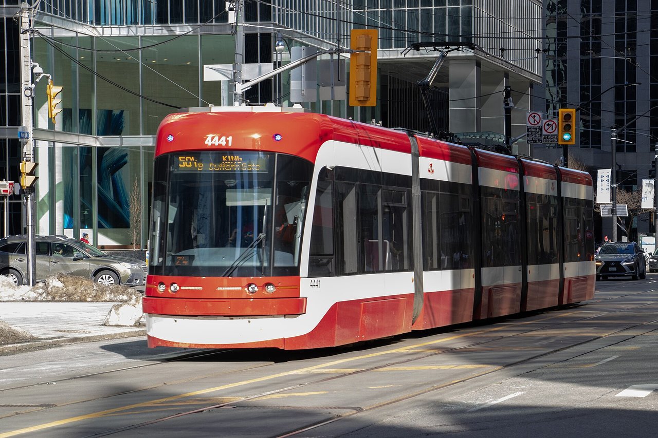 A red and white TTC streetcar running along King Street in downtown Toronto