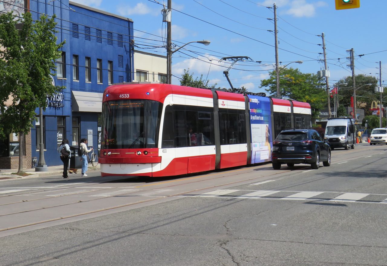 A red TTC streetcar running along Toronto's waterfront on Lake Shore Boulevard