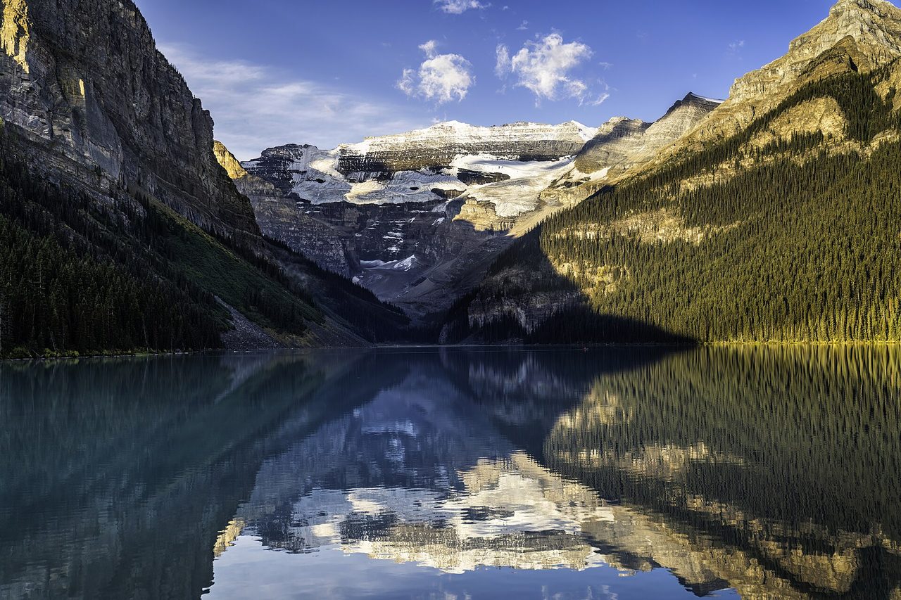 Lake Louise glowing turquoise in early autumn, golden larches on the shoreline beneath Victoria Glacier