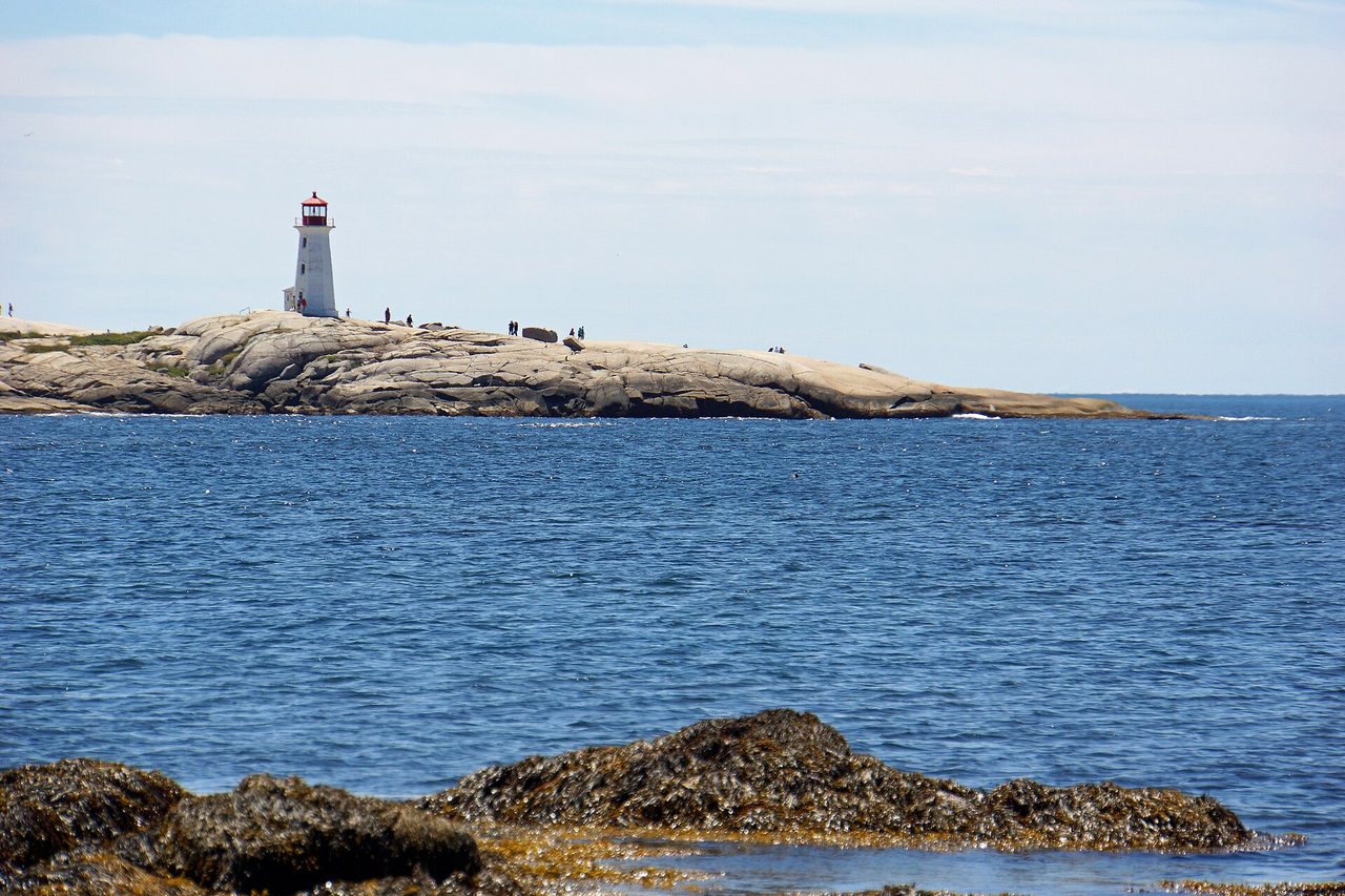 Peggy's Cove lighthouse standing on wave-washed granite rocks on an overcast Atlantic day