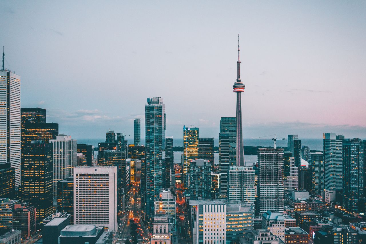 Toronto skyline and CN Tower glowing at dusk over Lake Ontario
