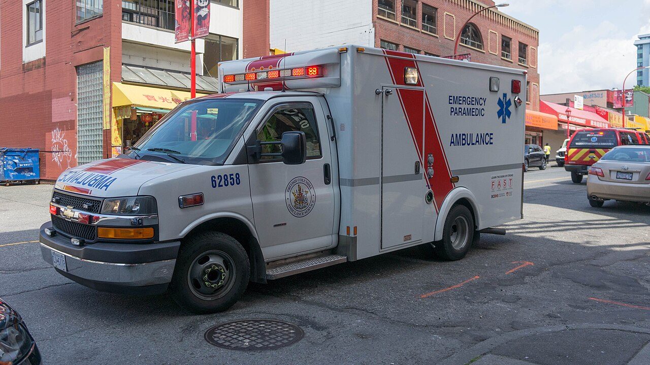 A British Columbia ambulance on a city street — one ride can cost an uninsured visitor hundreds of dollars