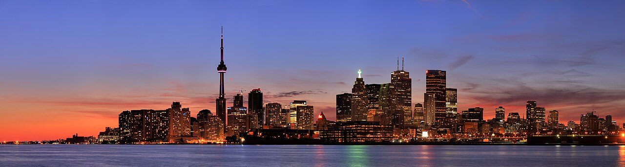 The Toronto skyline with the CN Tower glowing at dusk across Lake Ontario — plan the coverage before you plan the skyline photos