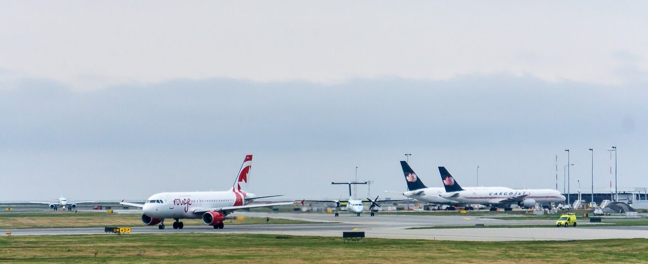 Commercial airliner taxiing on the tarmac at a Canadian airport under a cloudy sky