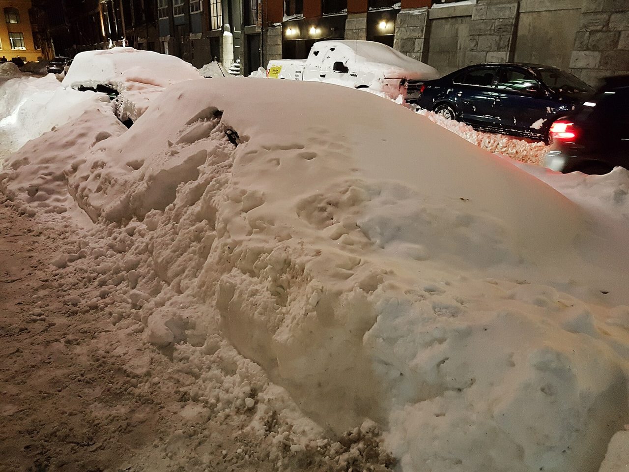 A car almost completely buried under snow after the March 2017 blizzard on a Montreal street