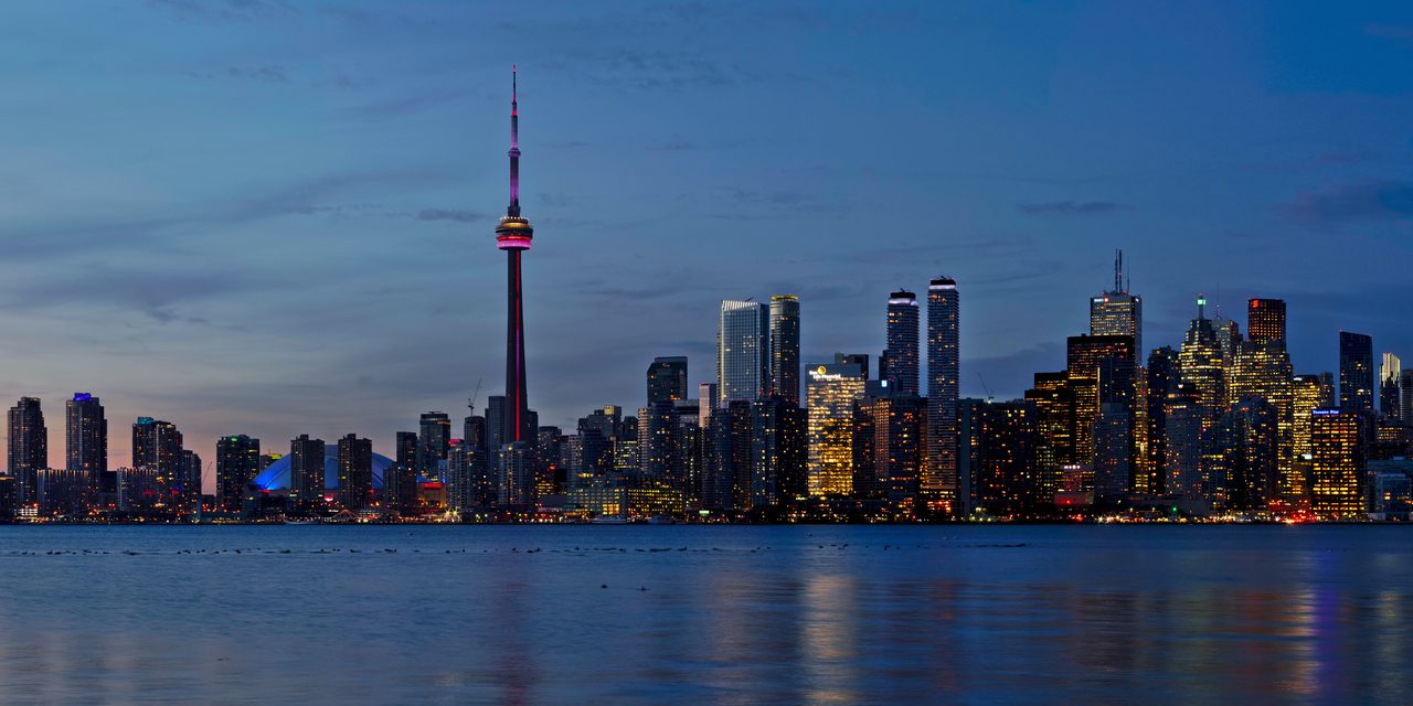 Toronto skyline at sunset with the CN Tower glowing over Lake Ontario