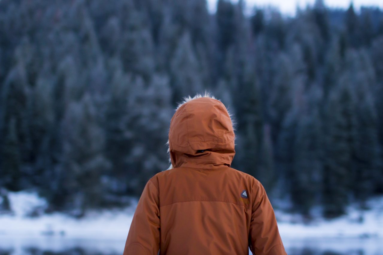 A traveler bundled in a warm hooded parka during a snowfall
