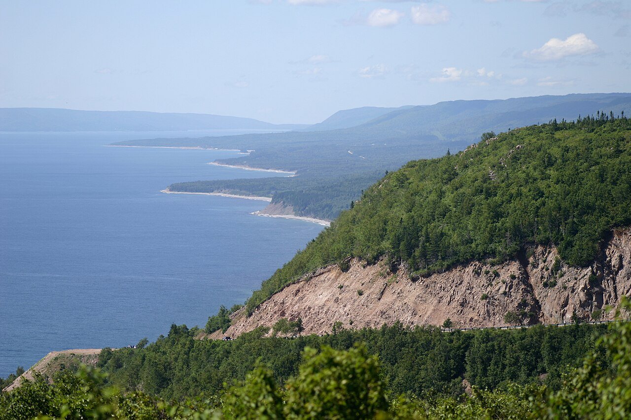 The Cabot Trail hugging steep forested cliffs along the coast at Cape Smokey