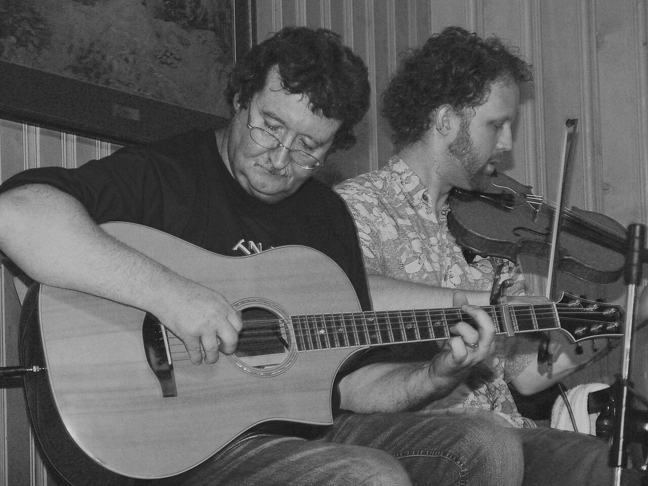 A fiddler and guitarist playing traditional music at a folk festival session