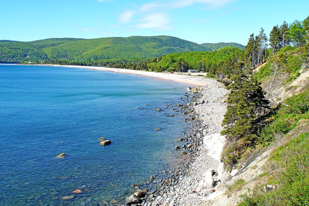 Ingonish Beach with calm shoreline curving along the coast backed by forested hills