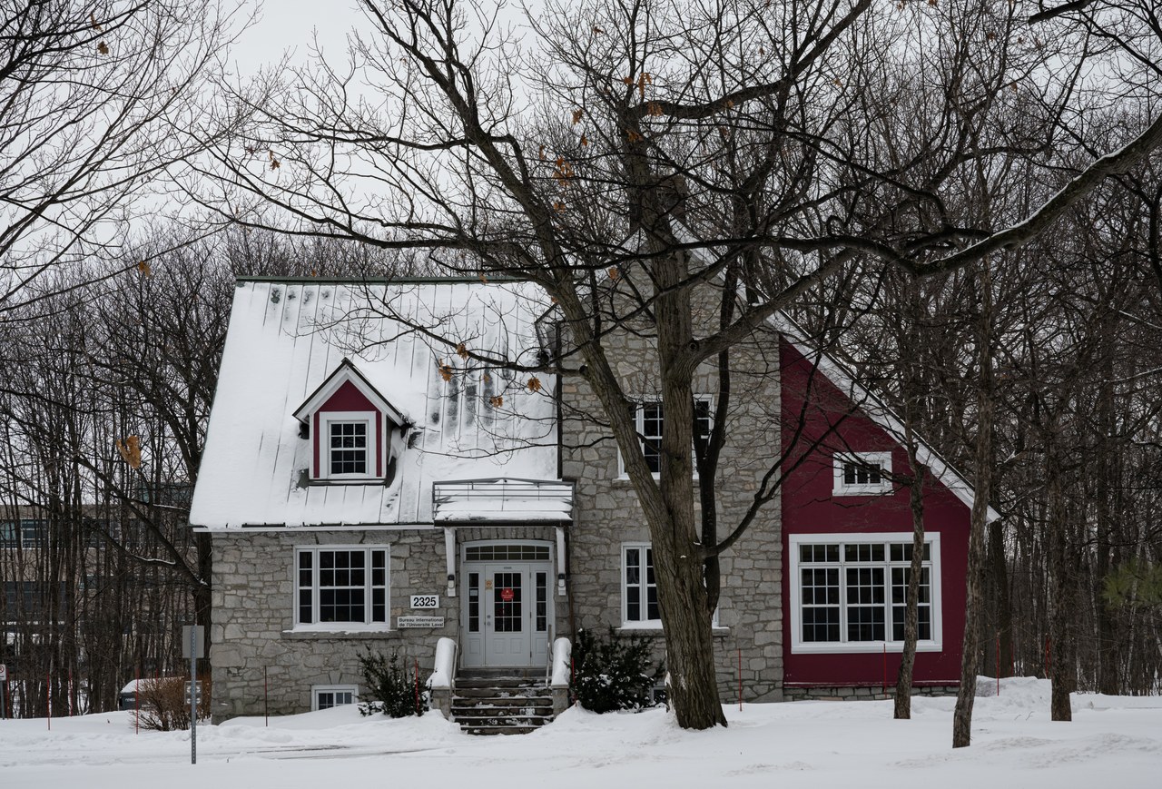 A red wooden house surrounded by deep snow near Quebec City in February, peak winter carnival season