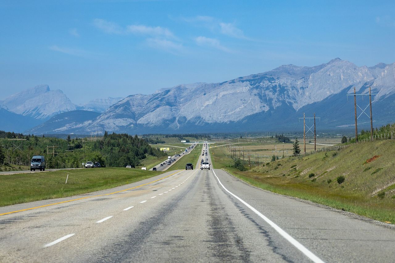 The Trans-Canada Highway running toward the Rocky Mountains in Alberta with a car on the open road