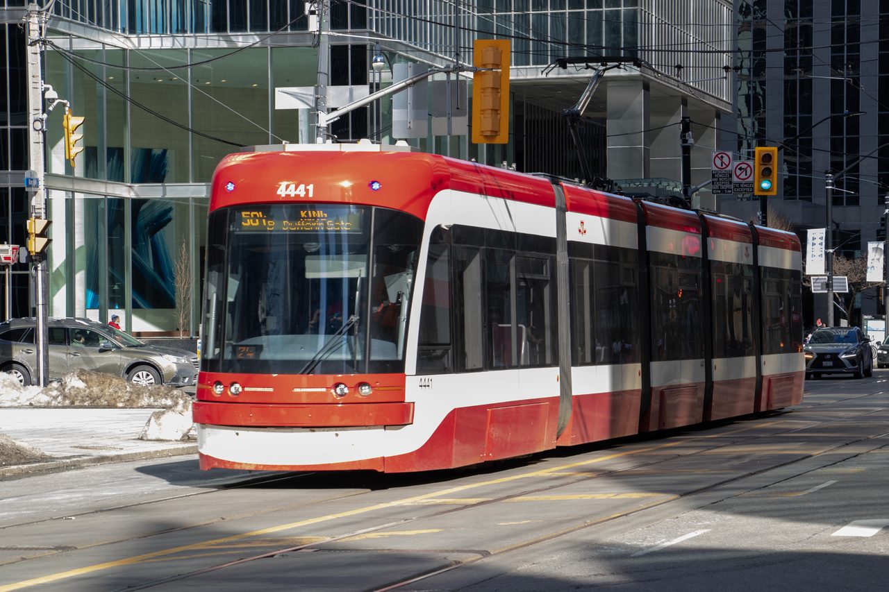 Red TTC streetcar rolling along King Street in downtown Toronto